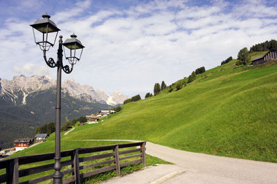 Street amidst green landscape against sky