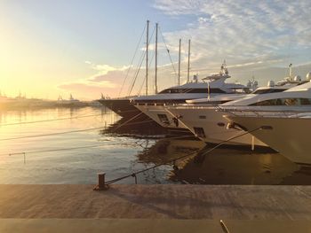 Yachts moored at harbor during sunset