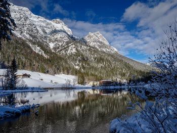 Scenic view of lake by snowcapped mountains against sky