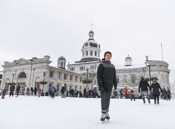 Teenage boy standing on outdoor skating rink on a cloudy day.