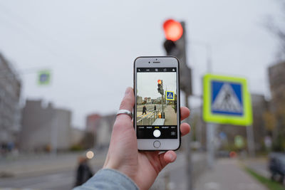 Red traffic light, in a man's hand holds a phone removes a pedestrian crossing, traffic rules