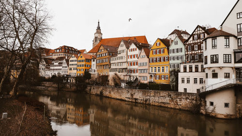 Residential buildings by river against clear sky