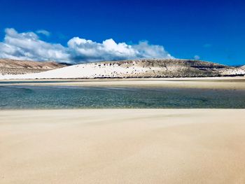 Scenic view of beach against blue sky