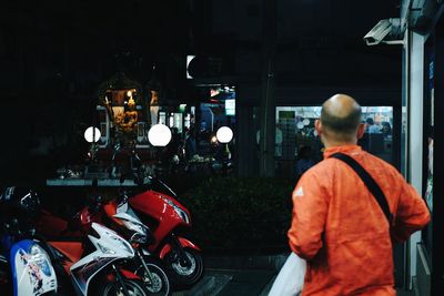 Rear view of man by shop at night
