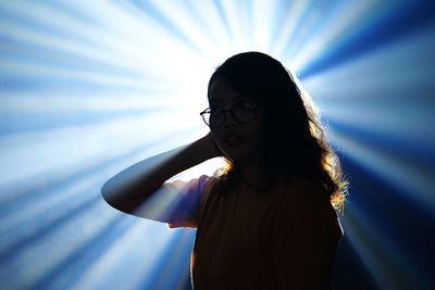 Young woman standing against light beams