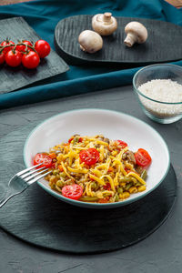 Risotto with beefs and cheese in a plate on a gray background on a black board near the ingredients.