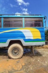 Close-up of yellow car parked on land against blue sky