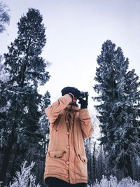 Man photographing on snow covered tree