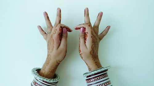 Cropped hands with henna tattoo gesturing against white background