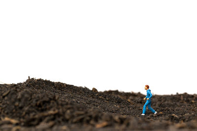 Side view of man standing on field against clear sky