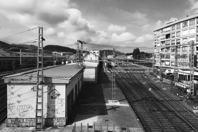 Railroad tracks amidst buildings in city against sky