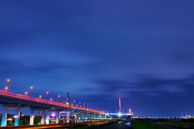 Illuminated bridge against blue sky in city at night