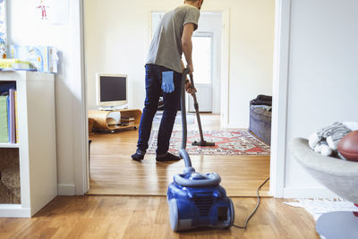 Rear view of man vacuuming carpet