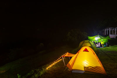 Illuminated tent on field against sky at night