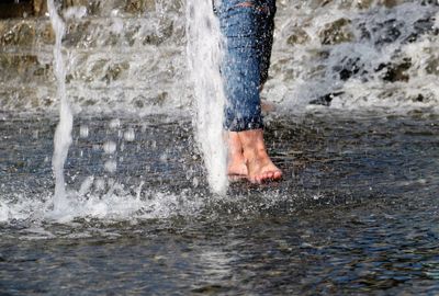 Low section of man splashing water in sea