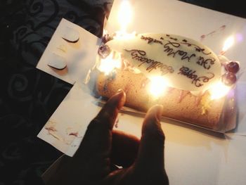 Close-up of hand holding burning candle