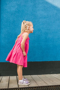 Full length of young woman standing on footpath