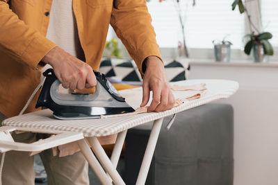 Person ironing his clothes, men's hands with iron, close up