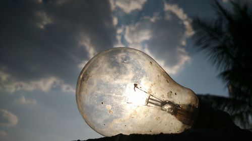 Close-up of damaged light bulb against sky