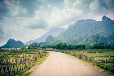 Road leading towards mountains against sky