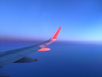 Close-up of airplane wing against clear blue sky