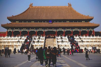 People at historic temple against clear sky