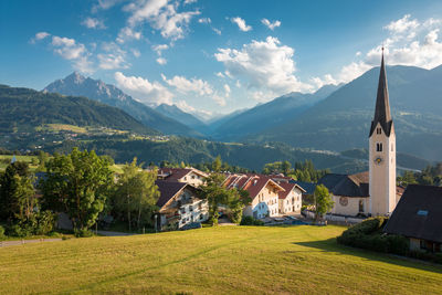 Houses amidst trees and buildings against sky