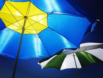 Low angle view of multi colored umbrella against clear blue sky