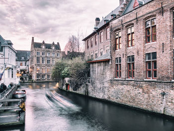 Canal amidst buildings in city against sky