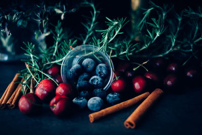Close-up of fruits with rosemary and cinnamons on table