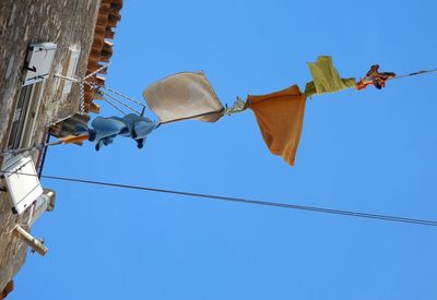 Low angle view of flags against clear blue sky