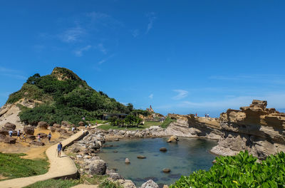 People at beach against blue sky