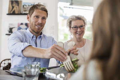 Smiling man serving salad to girl at home