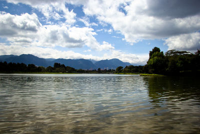 Scenic view of lake and mountains against cloudy sky