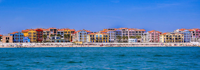 Buildings at waterfront against blue sky