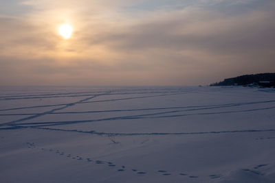 Scenic view of snow covered land against sky during sunset