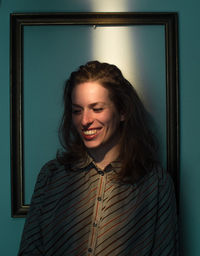 Mid adult woman standing against picture frame on wall