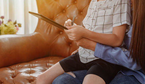 Midsection of woman sitting on sofa at home
