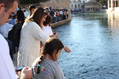 People standing by river in city