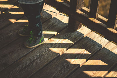 Low section of person standing on wooden boardwalk