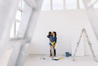 A young couple in love have moved into a new house and are making repairs painting white walls