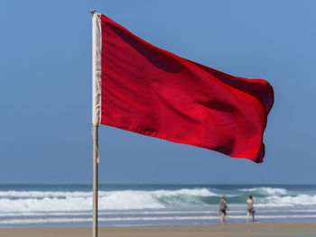 Red flag at beach against sky
