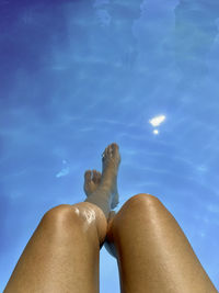 Low section of woman against blue sky