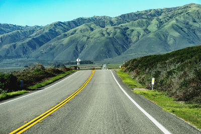 Road leading towards mountains against sky