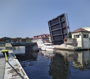 Boats moored in canal by buildings against clear sky