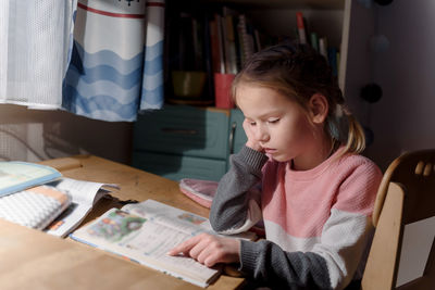 Little girl doing homework at home, homeschooling and distant education concept
