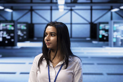 Young woman looking away while standing in city