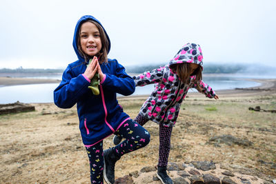 Sisters standing on water well against sky