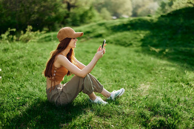 Side view of woman with hat standing on grassy field