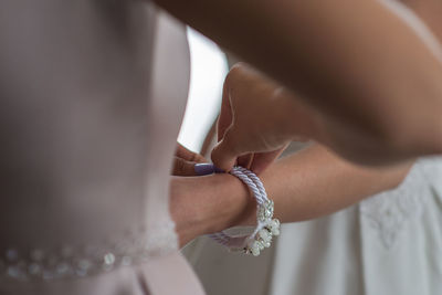 Close-up of woman getting bride dressed